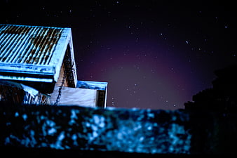 Rustic Roof Under Starry Night Sky with Blue Foreground