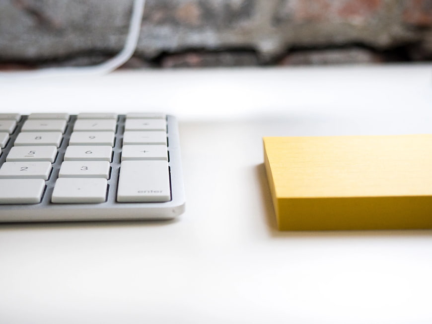 Minimalist White Desk with Keyboard and Yellow Notepad