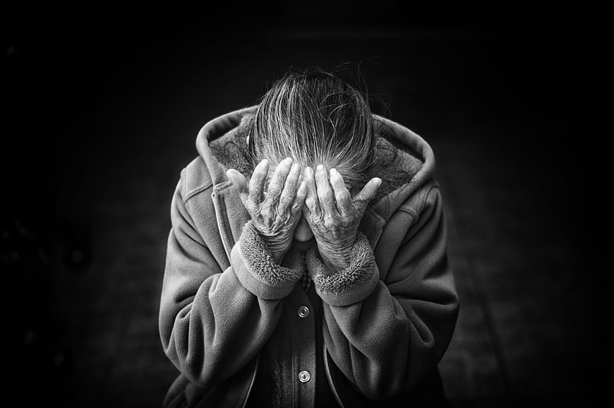Senior woman covering face in distress black and white
