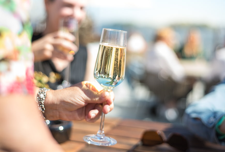 Hand holding champagne glass at outdoor summer party