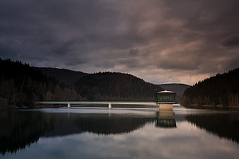 Dramatic Reservoir Bridge with Tower Under Stormy Sky
