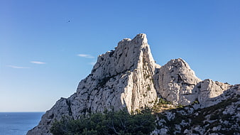 Dramatic limestone rock formation against blue sky and sea