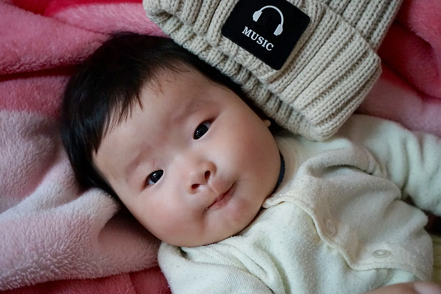 Cute Baby Lying on Pink Blanket with Beanie