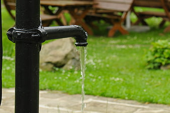 Black outdoor drinking fountain with flowing water in park