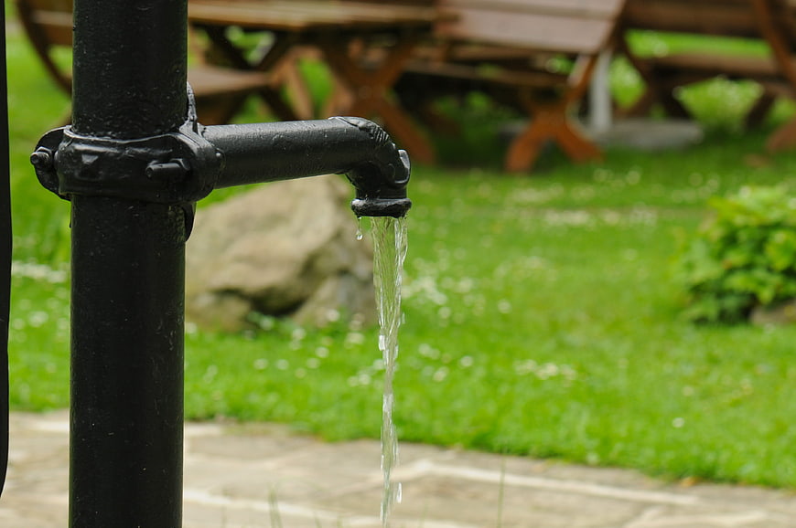 Black outdoor drinking fountain with flowing water in park