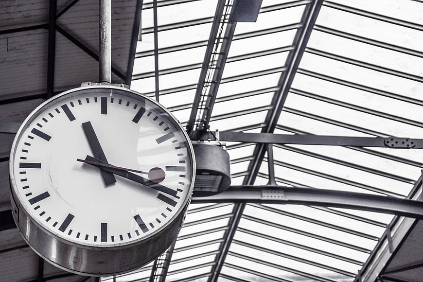 Vintage industrial clock hanging from glass ceiling structure