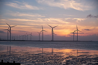 Offshore Wind Turbines Silhouette at Sunset Over Calm Water