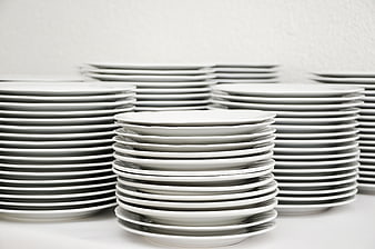 Stacks of white ceramic plates on a white table