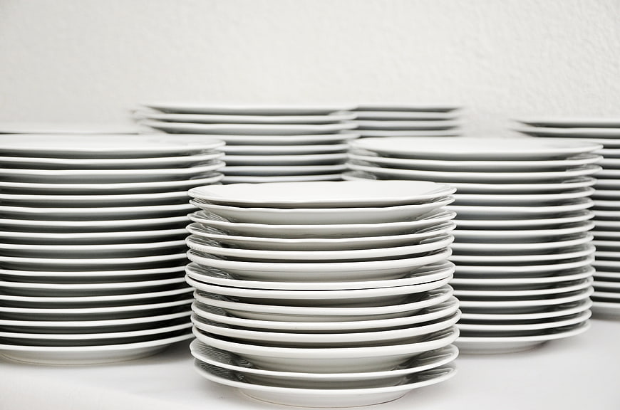 Stacks of white ceramic plates on a white table