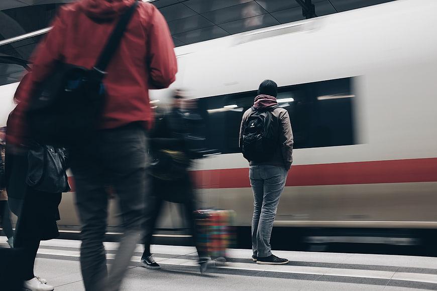 Man waiting on subway platform as train passes by