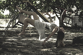 Young woman performing acrobatic backbend on dirt ground outdoors