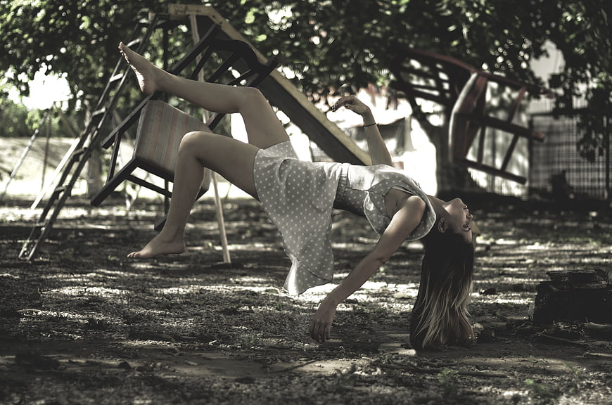 Young woman performing acrobatic backbend on dirt ground outdoors