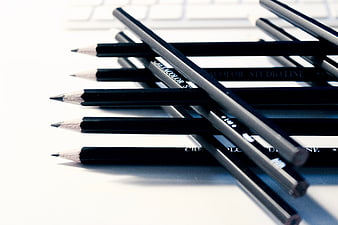 Black pencils on white desk with keyboard background