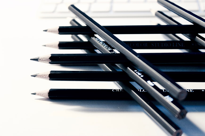 Black pencils on white desk with keyboard background