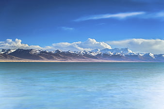 Serene turquoise lake with snow-capped mountains and blue sky