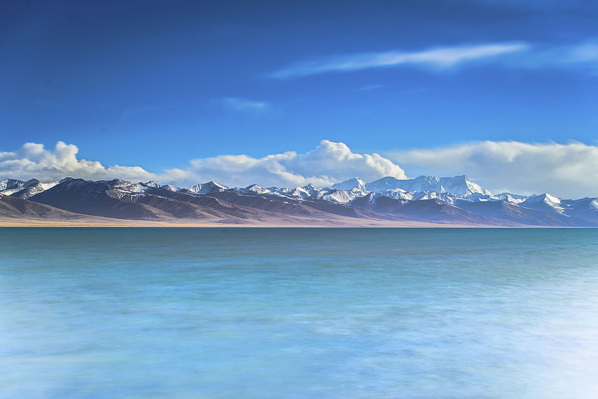 Serene turquoise lake with snow-capped mountains and blue sky