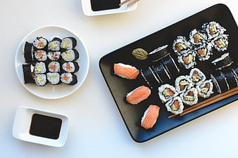 Top view of assorted sushi rolls and nigiri on black and white plates