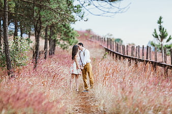 Romantic couple kissing in pink muhly grass field