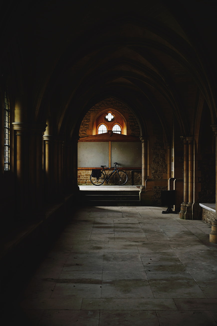 Dark Gothic Hallway with Bicycle in Sunlit Niche