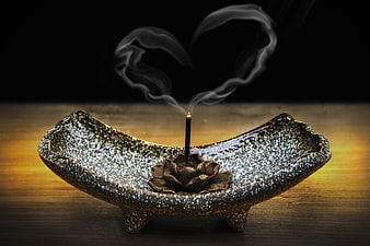 Incense smoke forming heart shape in ceramic bowl