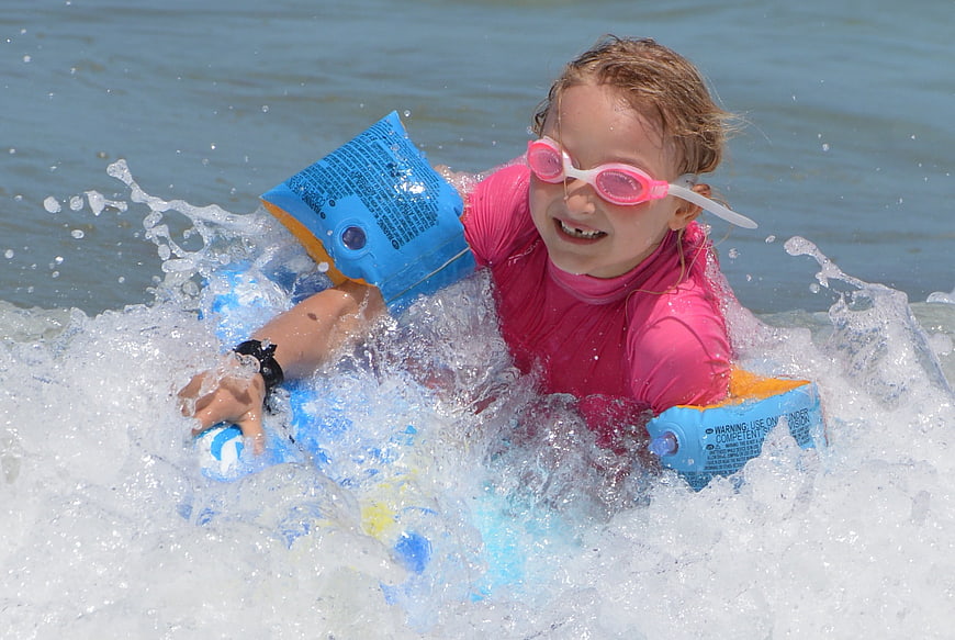 Happy Girl Surfing with Floaties and Goggles