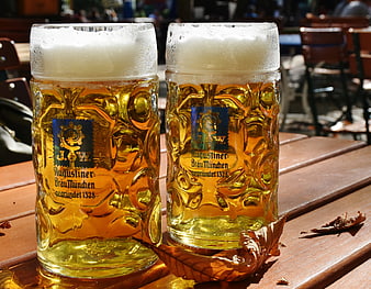 Two Augustiner beer mugs with foam on a wooden table