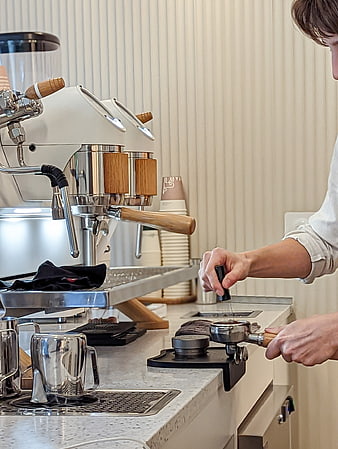 Barista Tamping Coffee Grounds in Modern Cafe