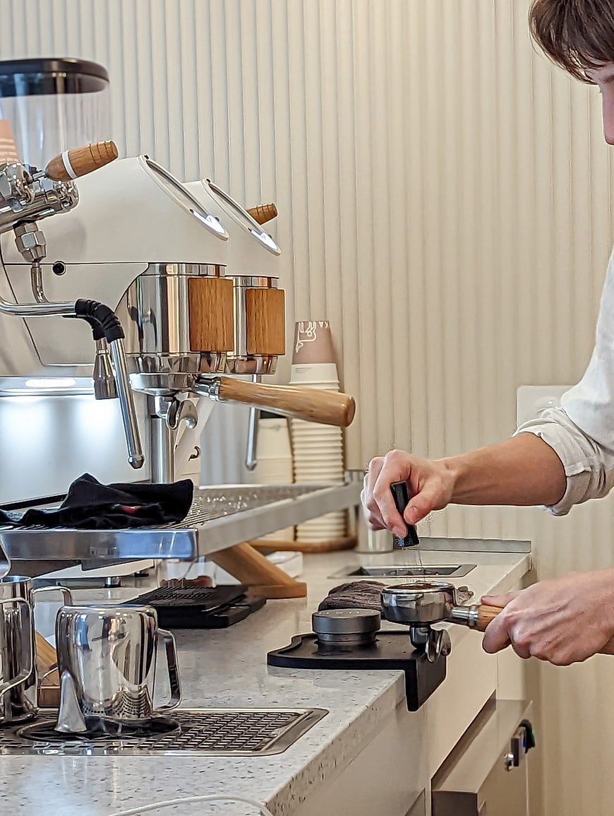 Barista Tamping Coffee Grounds in Modern Cafe