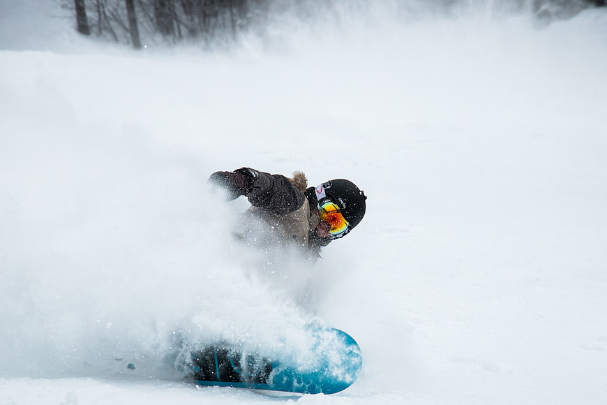 Snowboarder carving through deep powder snow