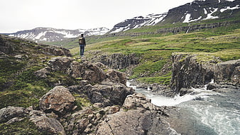 Hiker with backpack overlooking river canyon and snow-capped mountains
