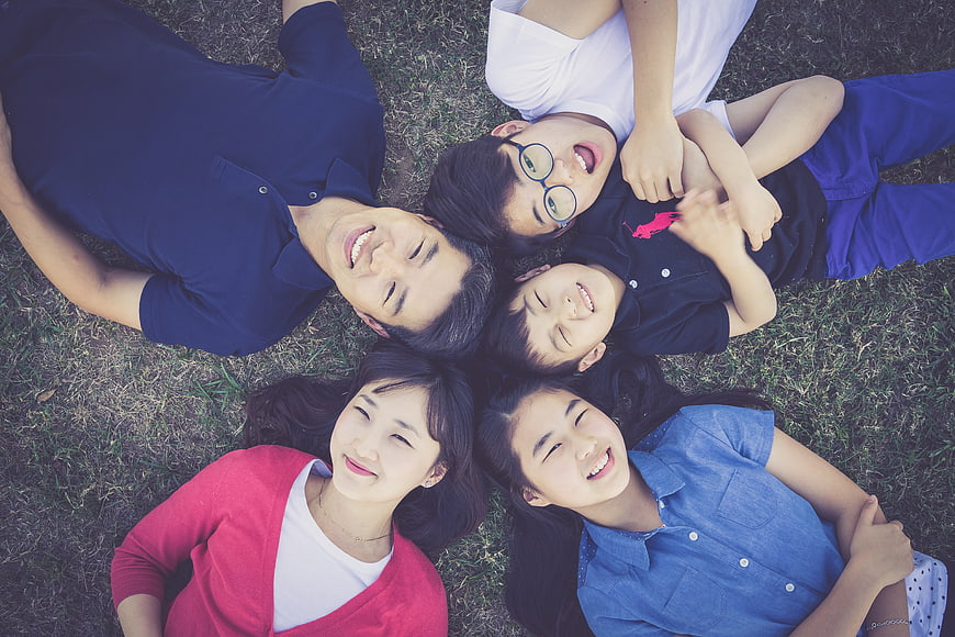 Happy Asian Family Lying On Grass In Circle