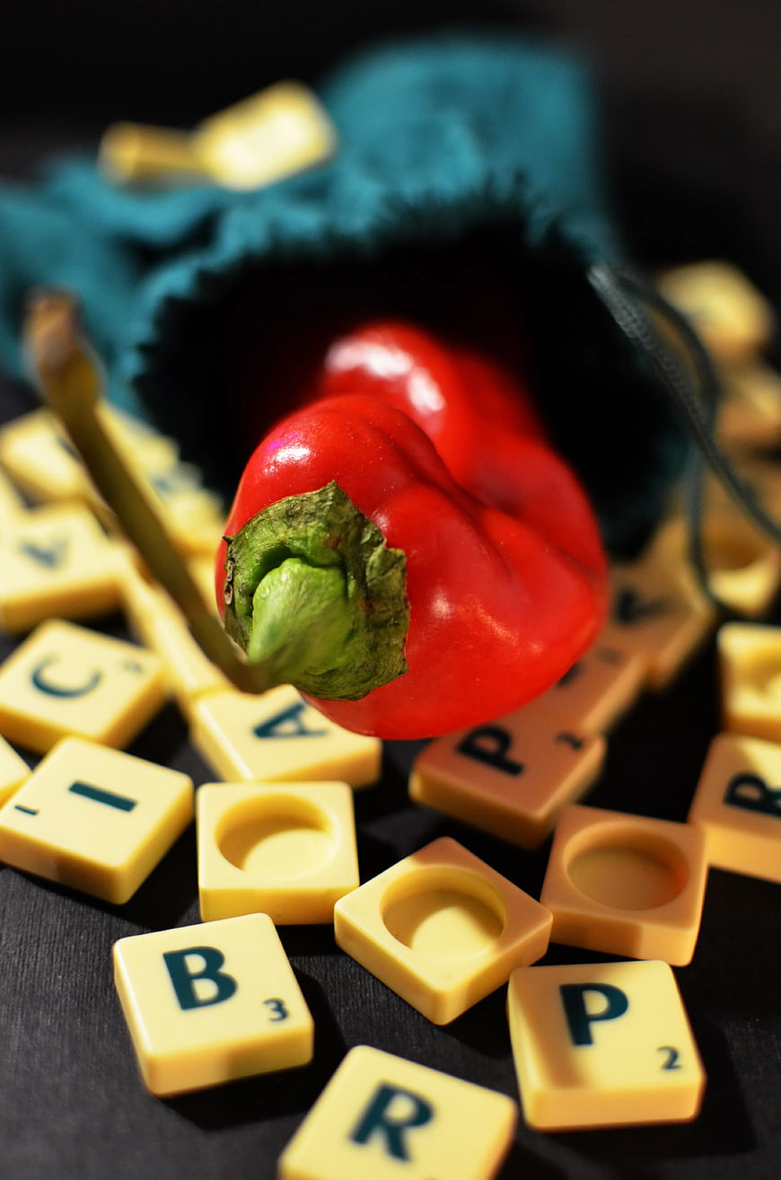 Red Habanero Pepper Spilling from Blue Bag onto Scrabble Tiles