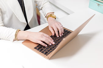 Businesswoman typing on gold laptop at white desk