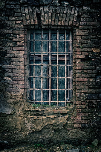 Old barred window in weathered brick wall