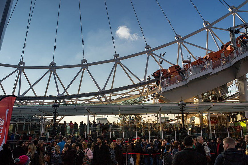 Crowd Waiting Under Large Ferris Wheel Structure