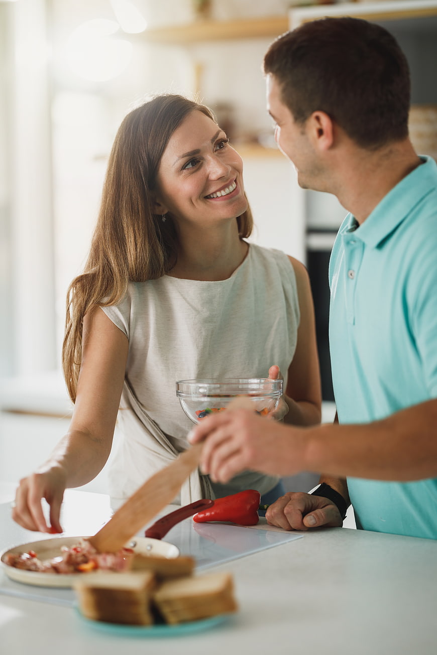 Happy couple cooking breakfast together in bright kitchen