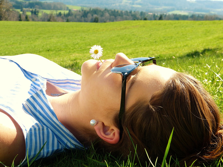 Relaxed Woman Lying in Green Meadow with Daisy