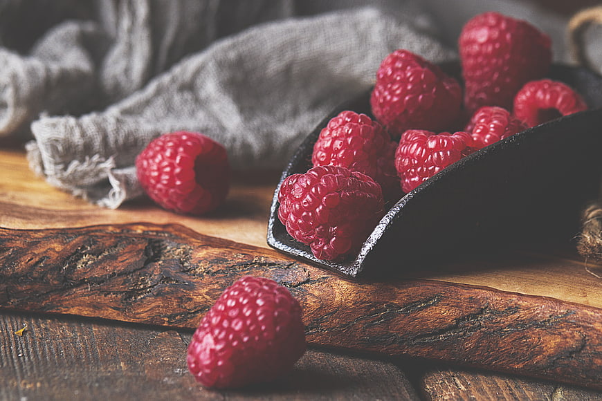 Fresh Raspberries in Black Scoop on Rustic Wood