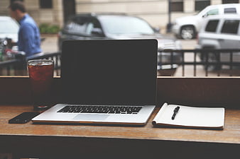 Laptop workspace with iced coffee and notebook on wooden table