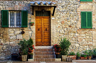 Medieval Stone House Facade With Wooden Door And Green Shutters