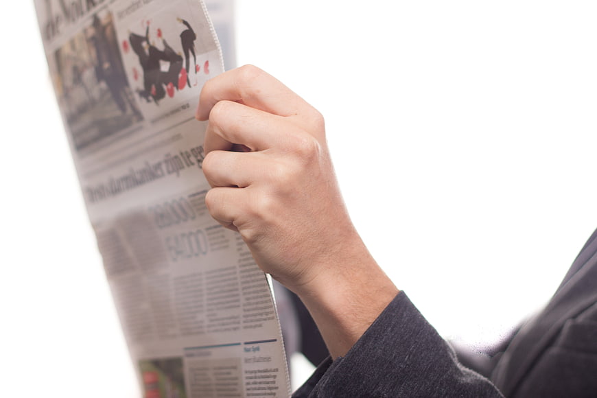 Hand holding newspaper with white background