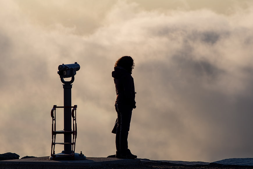 Silhouette of Woman Standing Next to Coin-Operated Binoculars