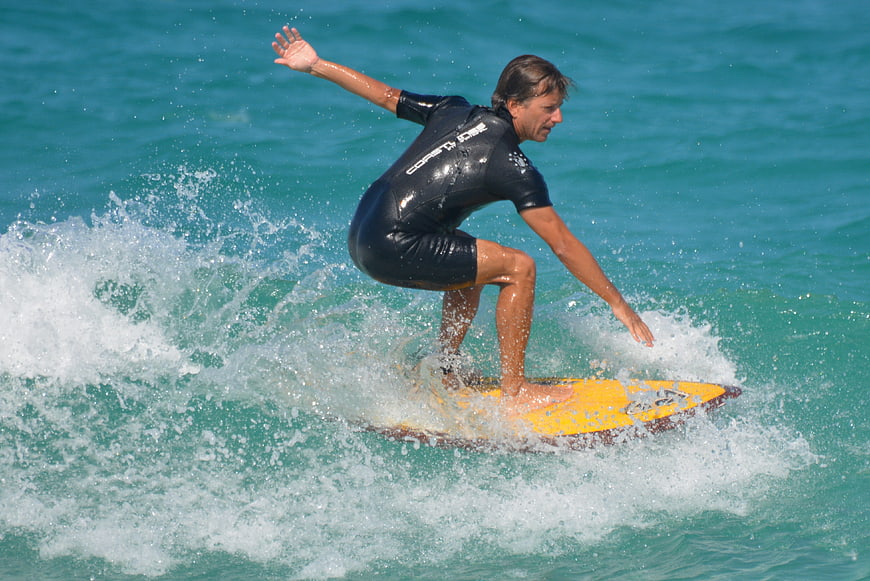 Man surfing on yellow board in turquoise ocean