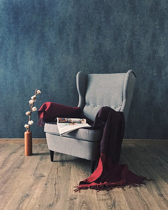 Cozy gray armchair with red blanket against blue textured wall