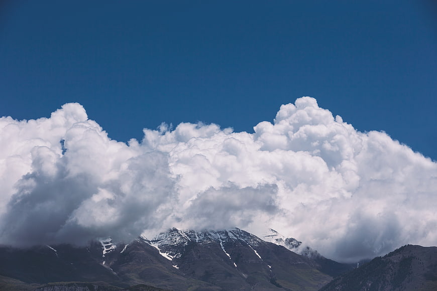 Snow-capped mountain peaks emerging from dramatic white clouds