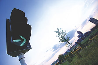 Green Arrow Traffic Light Signal Against Blue Sky