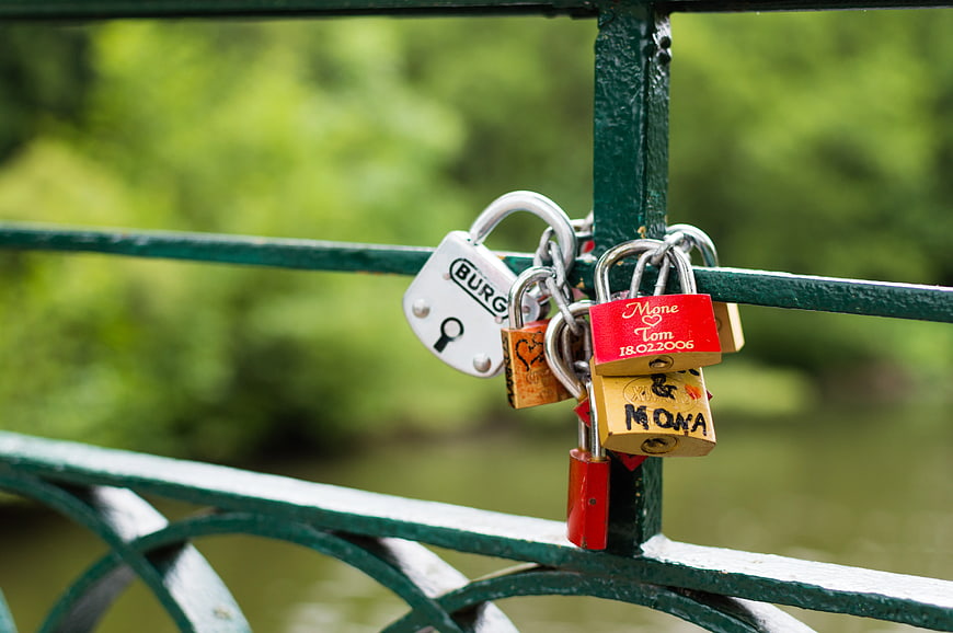 Love padlocks on green bridge railing with blurred nature background