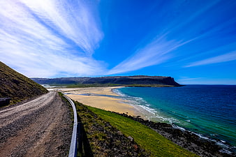 Scenic coastal road leading to sandy beach and blue ocean