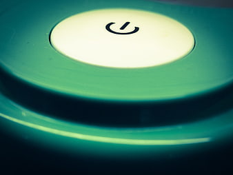Close-up of a glowing white power button on a teal electronic device