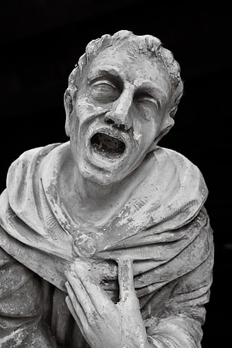 Black and white statue of a screaming man in despair